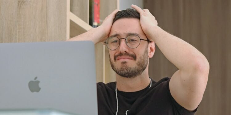 a man with glasses is looking at a laptop