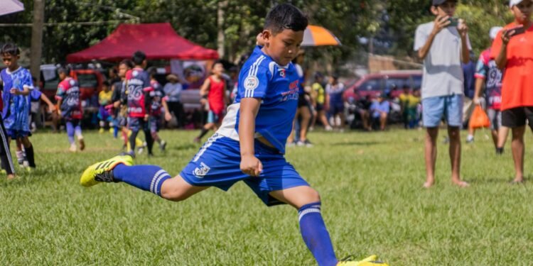 a young boy kicking a soccer ball on a field